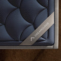 Corner detail of the DreamCloud Luxe 14-inch mattress featuring the premium branded corner strap and intricate quilted performance fabric.
