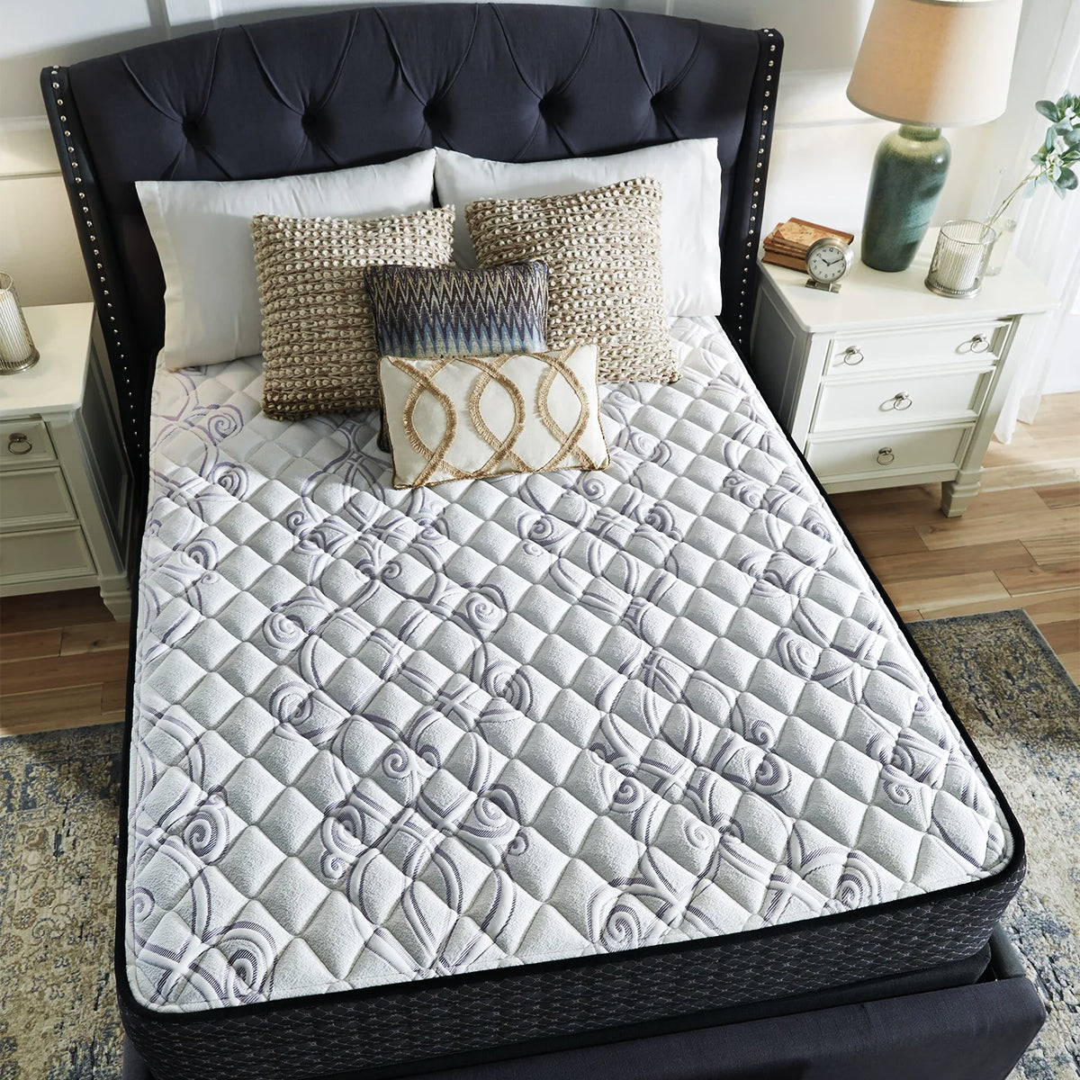 Top view of Ashley Sierra Sleep 12 Inch Plush Mattress on a stylish tufted bed with decorative pillows.
