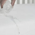 Waterproof test showing liquid beading on the cover of this organic mini crib mattress.