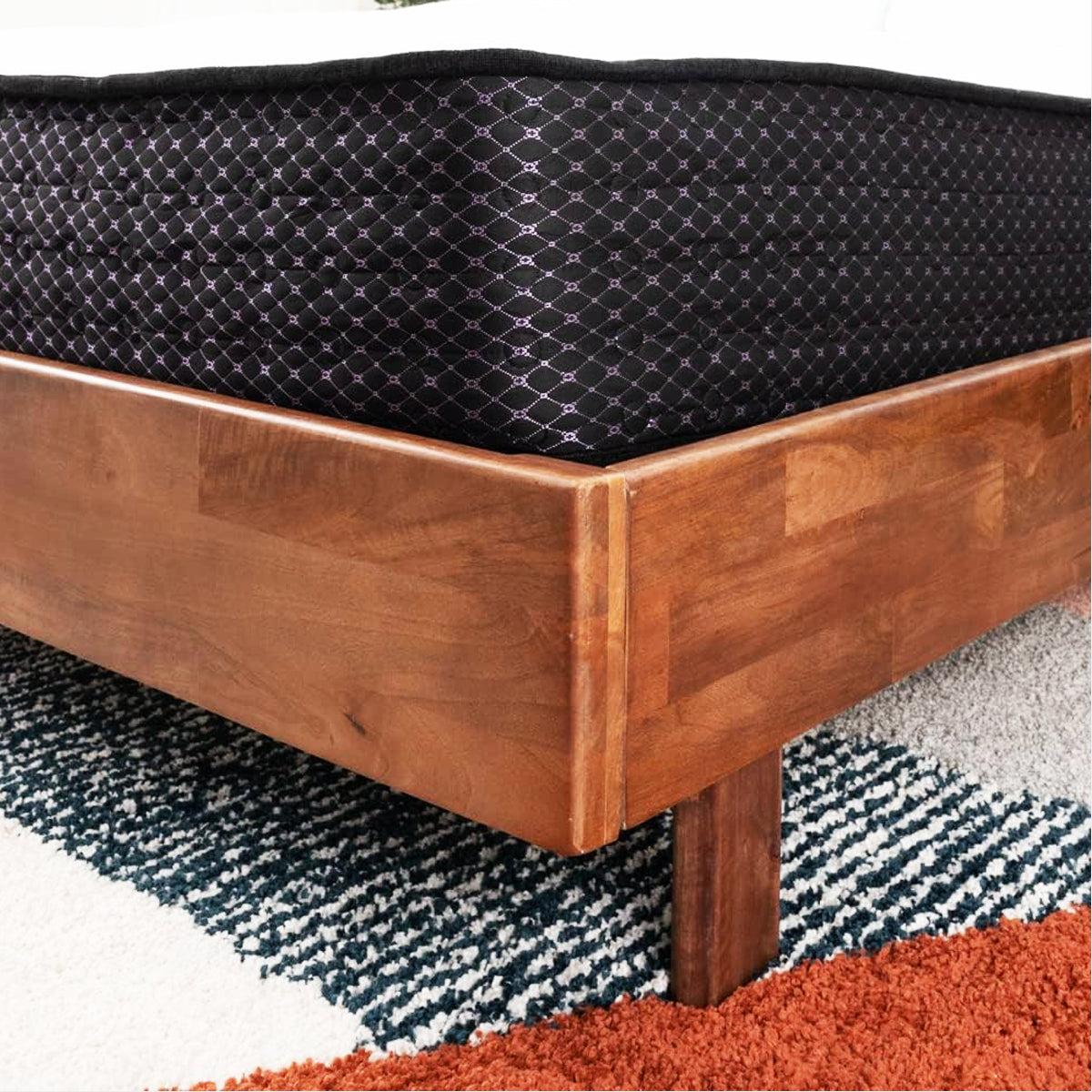 Detailed corner view of the Ashley Sierra Sleep 12 Inch Plush Mattress on a solid wood bed frame.
