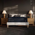 Symmetrical front-facing view of the DreamCloud Ultra Medium Hybrid Mattress styled in a designer bedroom with natural wood nightstands.
