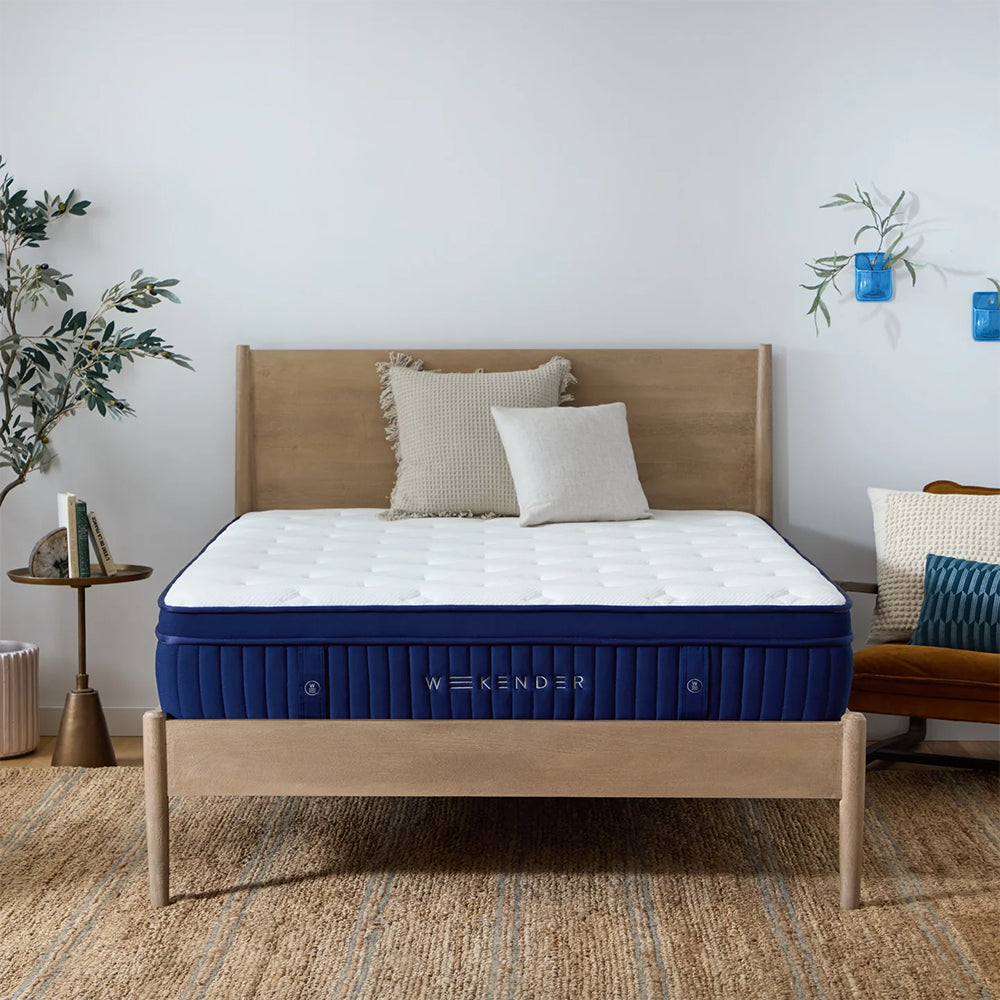Full frontal view of the Weekender 11-inch Euro Top Hybrid mattress styled on a natural wood platform bed in a bright, modern master bedroom.
