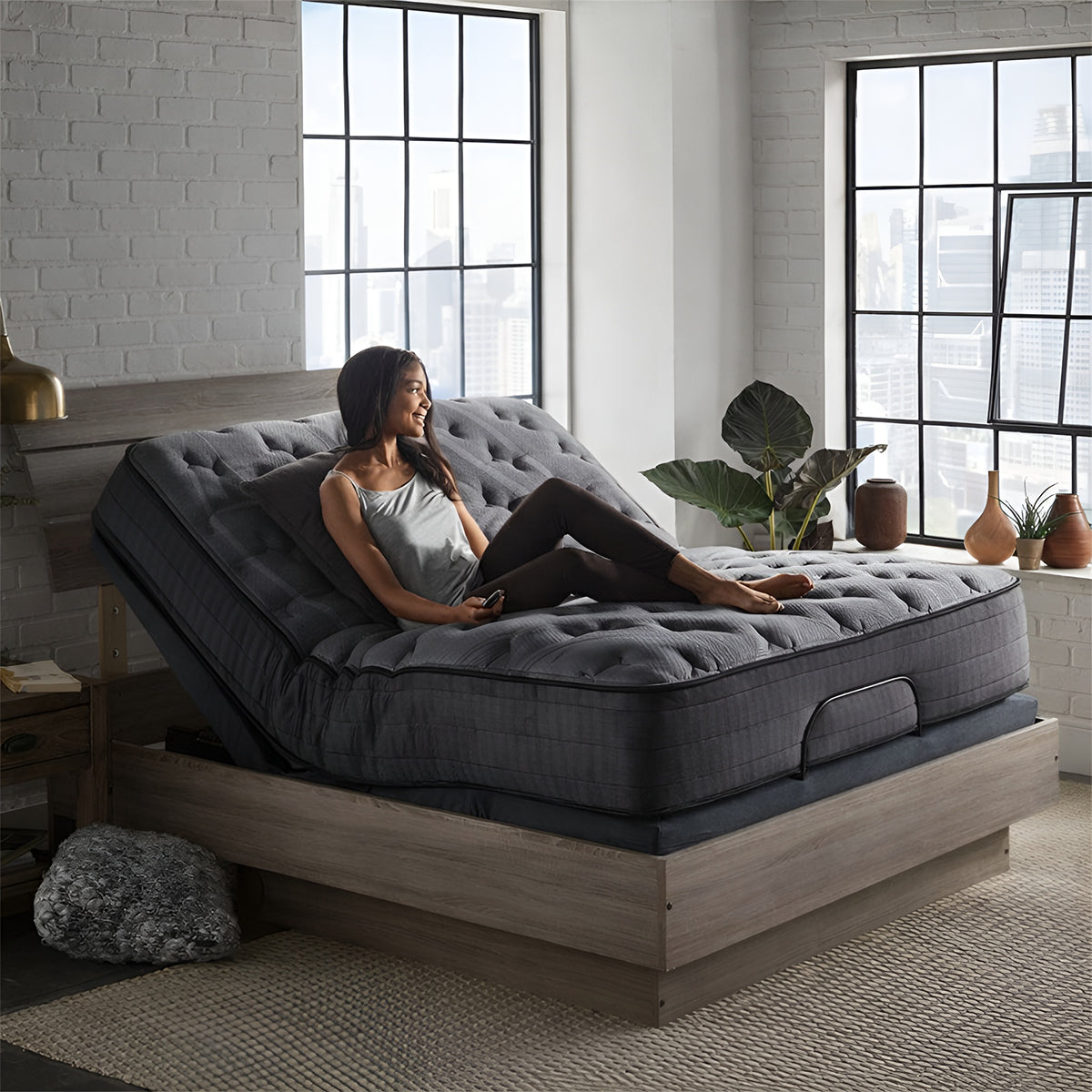 Nights Bridge 12-inch plush hybrid mattress by Corsicana elevated on an adjustable power base in a modern bedroom with large windows.

