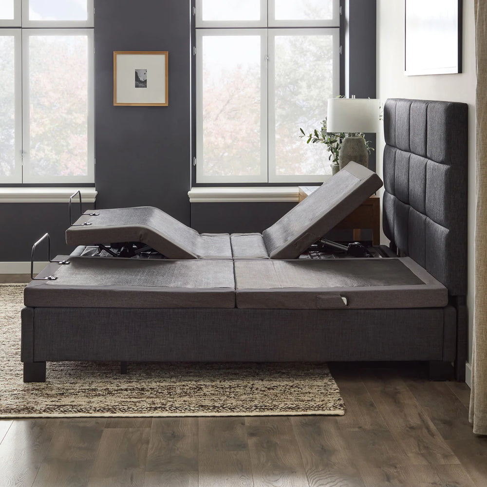 Side lifestyle view of the Malouf M455 power base within a bed frame demonstrating independent head and foot elevation for couples.
