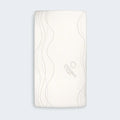 Top view of Bundle of Dreams organic cotton crib sheet with a grey wave pattern for a modern nursery.
