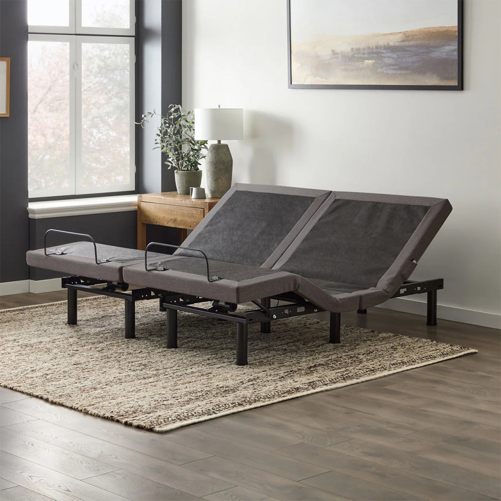 Malouf M455 split king adjustable bed base in a modern bedroom lifestyle setting with head sections elevated for reading.
