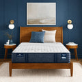 Serta iComfortPRO Quilted Ambrose firm 13 inch mattress on a wooden bed frame in a modern blue bedroom.
