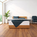 SleepFresh 12" Medium Hybrid Mattress in bedroom setting styled with a wooden frame and navy blue accent bedding.