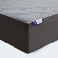 Macro shot of the Neve 12-inch mattress corner showcasing the premium textured grey cooling fabric and durable charcoal side panels.
