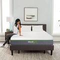 A woman sitting on the edge of a GhostBed Elite memory foam mattress, demonstrating the mattress's edge support and 12-inch medium comfort profile.
