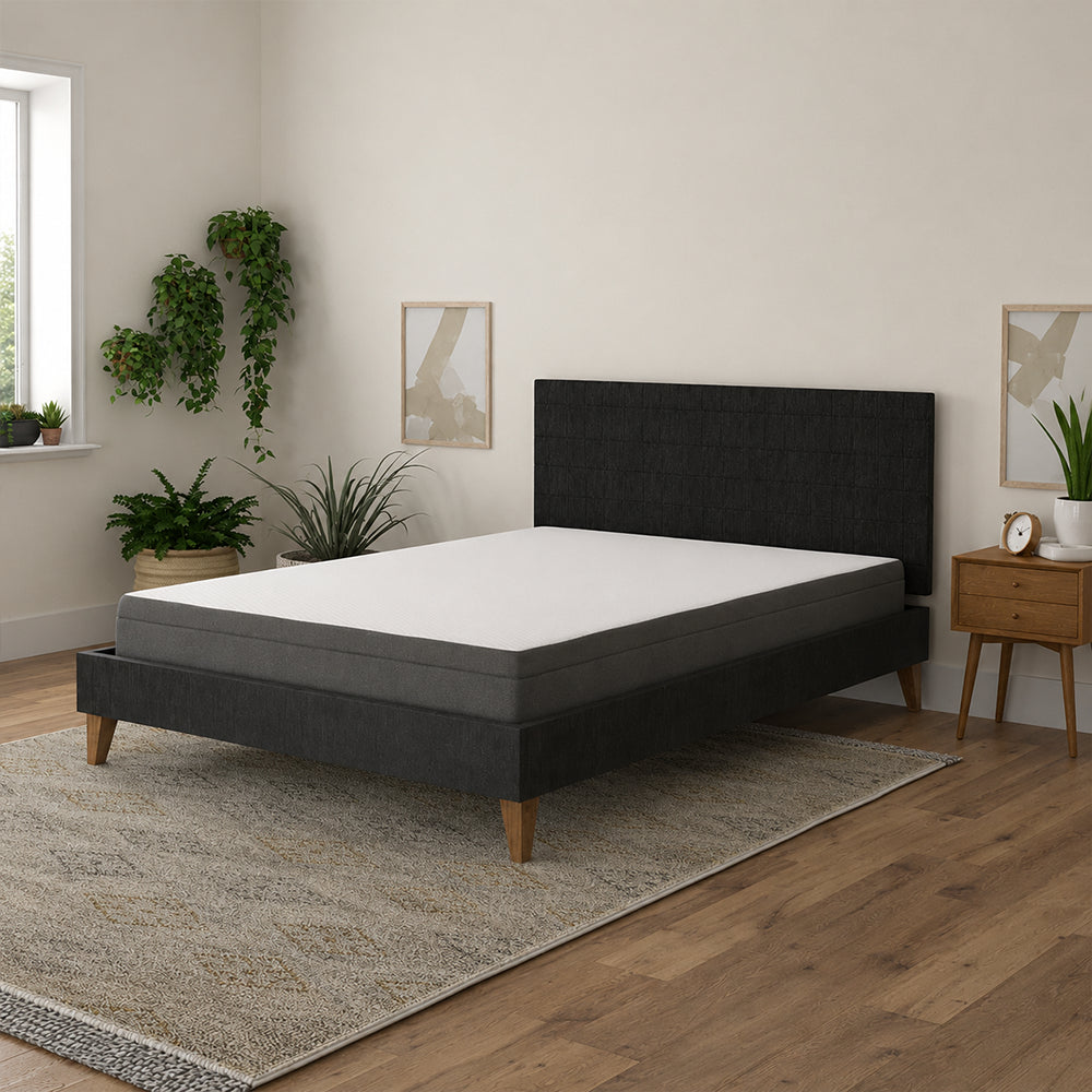 Wide-angle shot of the Daisy firm mattress by South Bay in a stylish bedroom featuring hardwood floors and large windows.
