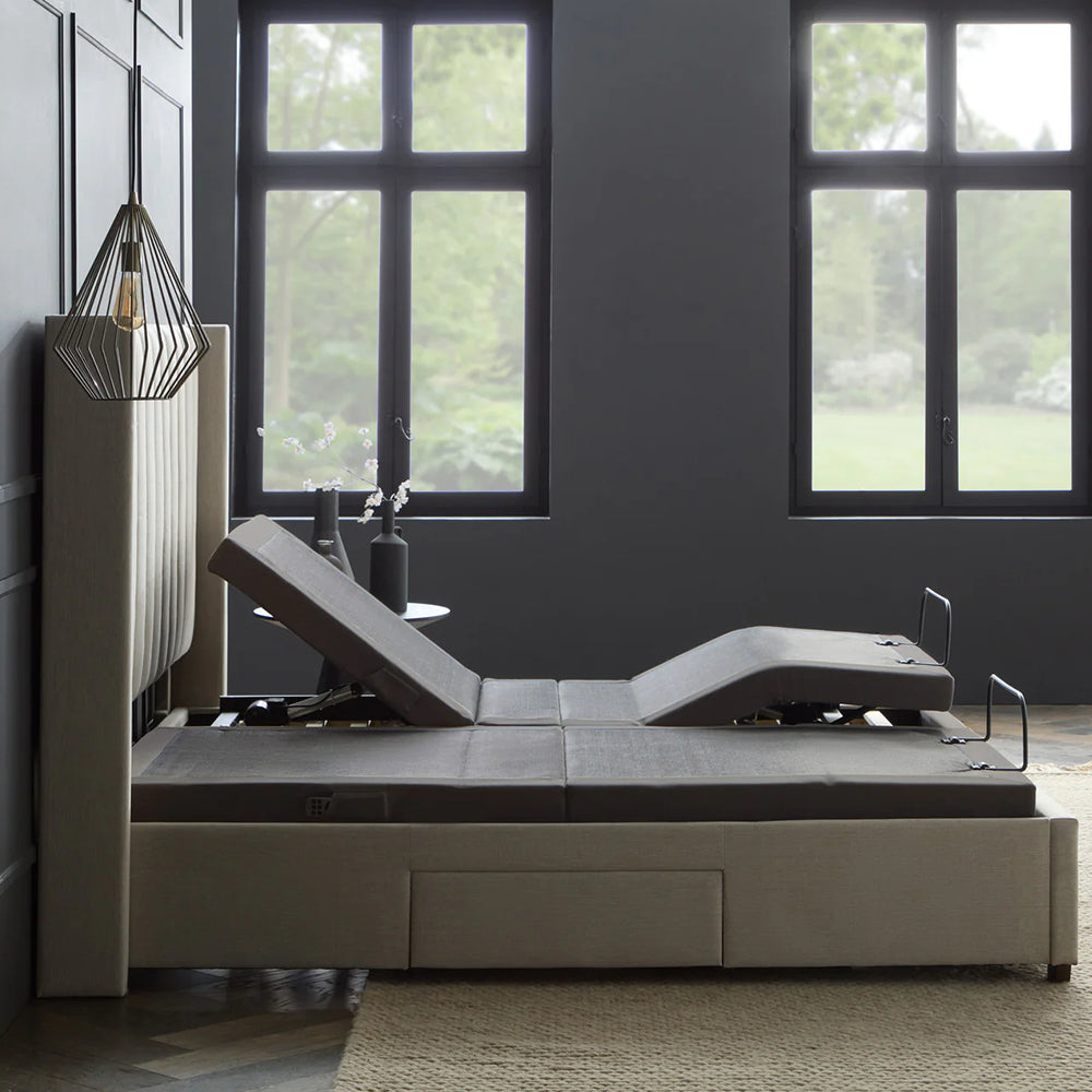 Split King Malouf S655 adjustable bed base set inside a luxury beige upholstered platform bed frame with a fluted headboard.
