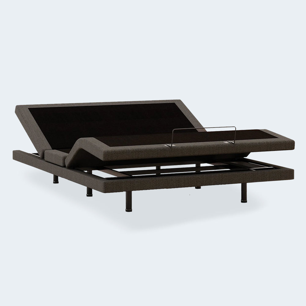 Three-quarter view of the Ashley Comfort Ultra motorized bed base showing charcoal grey upholstery and sturdy steel legs.

