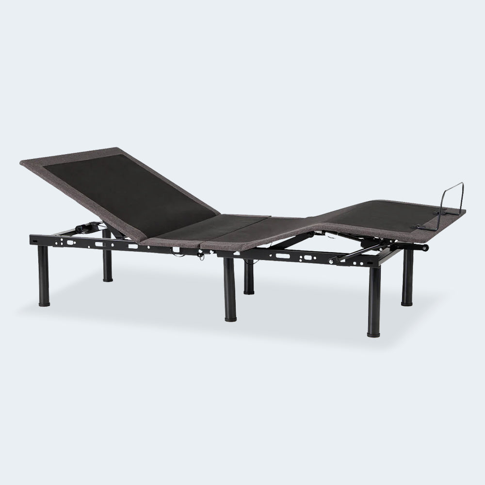 Three-quarter perspective of the Malouf E455 motorized bed base showing head and foot articulation with premium light grey upholstery.
