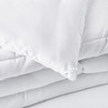 Detailed shot of the SleepTone Goto white comforter's soft microfiber fabric and durable box stitching.
