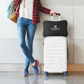 Portable BEDGEAR Storm travel pillow in its black case attached to the handle of a white rolling suitcase.
