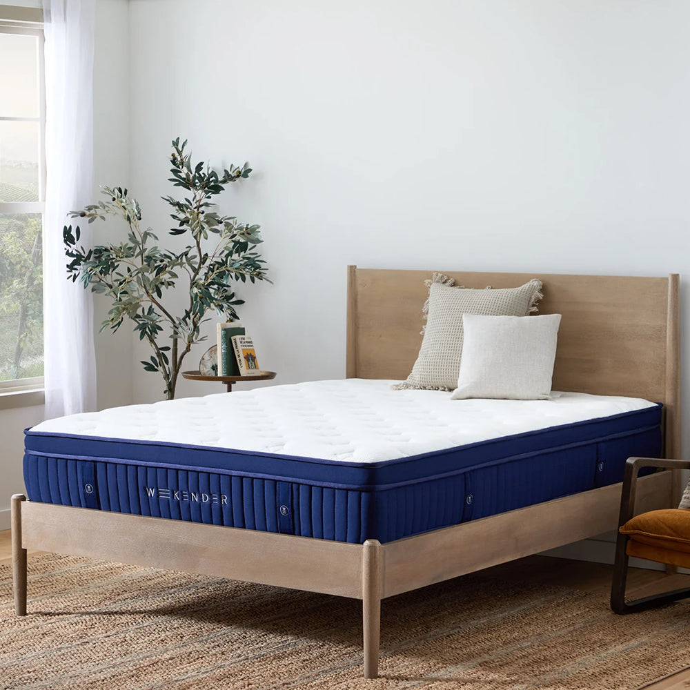 Three-quarter angle view of the Weekender 13-inch medium plush mattress styled in a contemporary bedroom with natural wood furniture.
