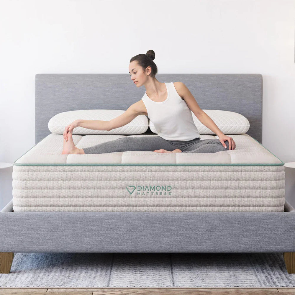 Woman stretching on the supportive Sage Organic Latex hybrid mattress, demonstrating the stable surface and medium-firm comfort of Diamond Mattress.
