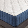 Macro detail shot of the GhostBed Grande logo and textured navy side quilting on a luxury 14-inch cooling mattress.
