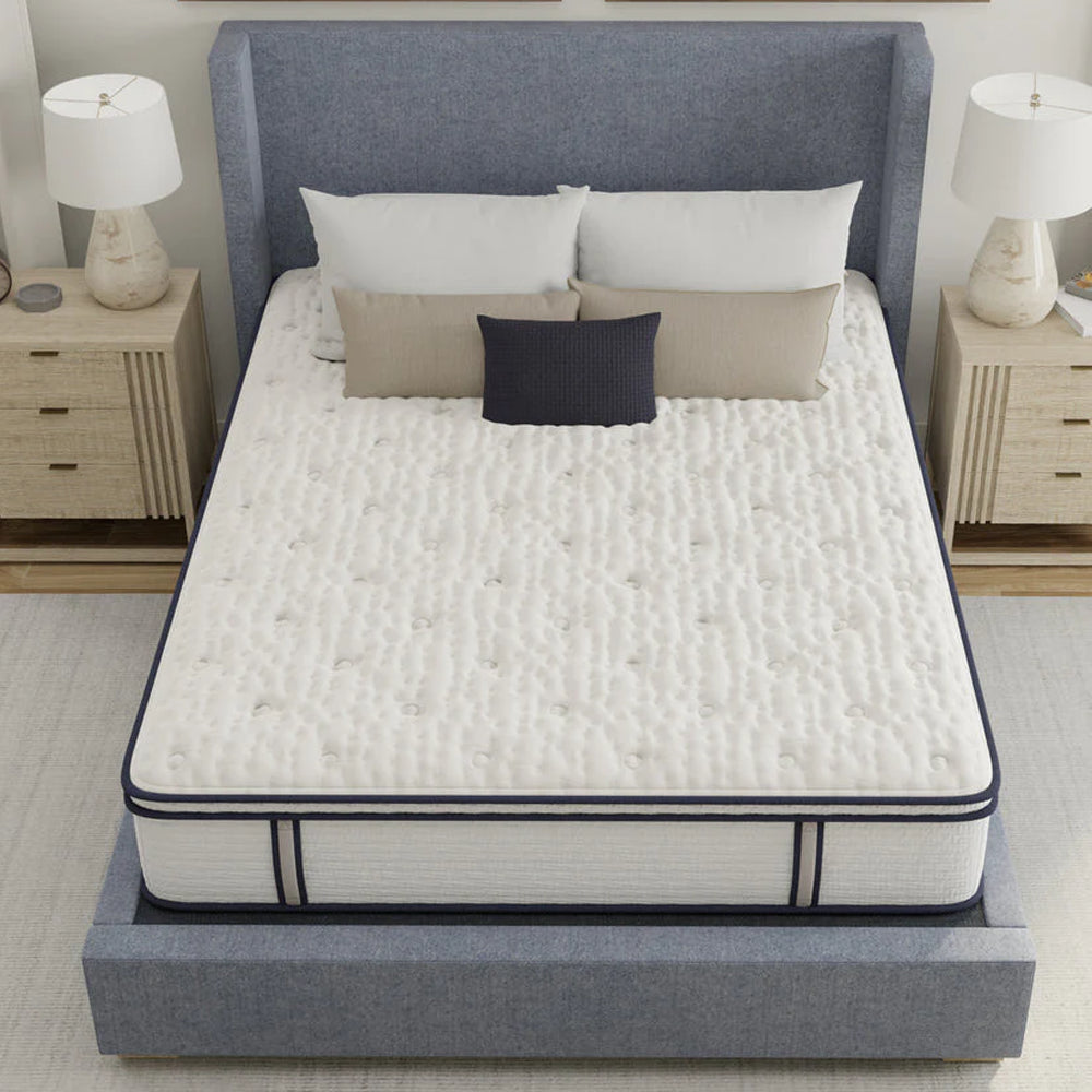 High-angle view showing the white tufted quilted surface of the South Bay Sofinity Hybrid Signature mattress on a contemporary blue bed frame.
