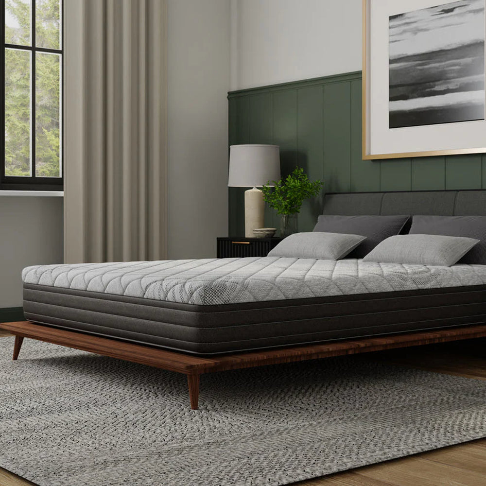 Three-quarter angle of the Essentials 10-inch firm memory foam mattress by South Bay, showcasing the light grey quilted top and charcoal side panels.
