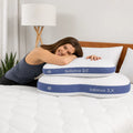 Woman smiling while hugging a BEDGEAR Balance pillow on a bed, showcasing plush and cozy sleep comfort.