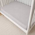 Grey BEDGEAR Hyper-Wool crib sheet on a white wooden crib for temperature-regulating infant sleep.
