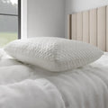 Malouf HyperChill pillow protector on white bedding for an instant cooling sleep surface.
