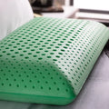 Malouf Zoned Dough peppermint pillow on a bed with ventilated holes for ergonomic neck support and airflow.
