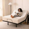 Lifestyle bedroom view of a woman sitting on an MLILY MS 300 adjustable bed base with the head elevated for comfortable reading.
