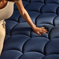 A hand pressing into the scalloped surface of the DreamCloud Ultra mattress to demonstrate the contouring memory foam and responsive support.