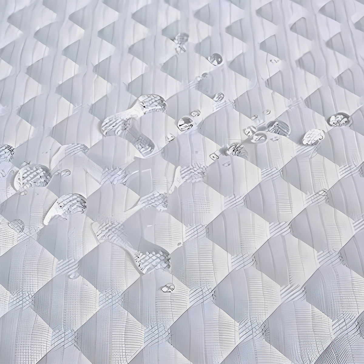 Water droplets on the diamond-patterned cover of a Celsius Organic Cotton 2-Stage Crib Mattress.
