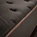 Detailed close-up of the charcoal grey quilted surface and copper-toned piping of the Tommie Copper Core Znergy recovery mattress.
