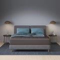 Tommie Copper Core Znergy Mattress styled in a modern bedroom with grey headboard and blue pillows.