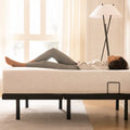 Side profile lifestyle shot of a woman lying on an MLILY MS 300 adjustable bed base in its neutral flat position.
