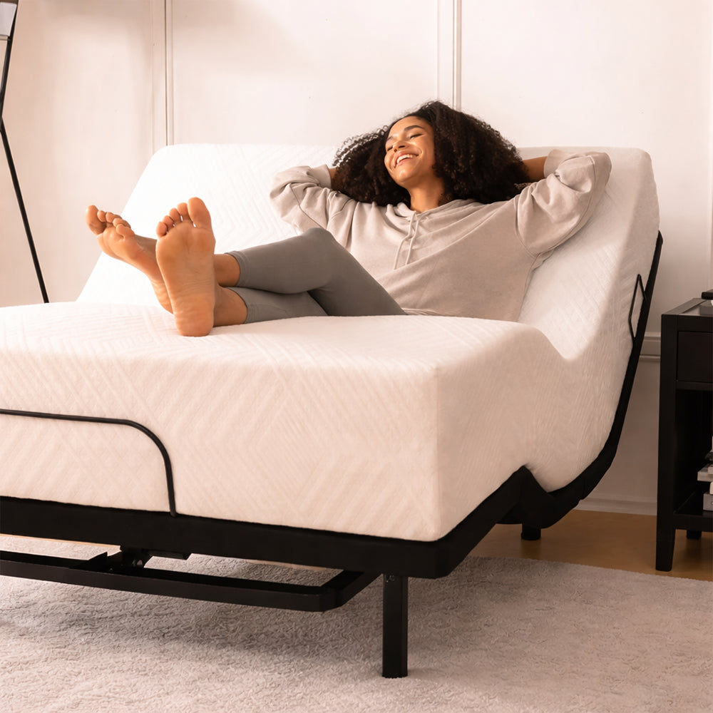 Lifestyle image of a woman relaxing on an MLILY MS 200 adjustable bed base with a mattress, showing head and foot elevation for lounging.
