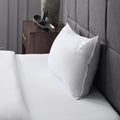 Malouf white bed pillow with Z logo detail propped against a stylish grey headboard for bedroom decor.

