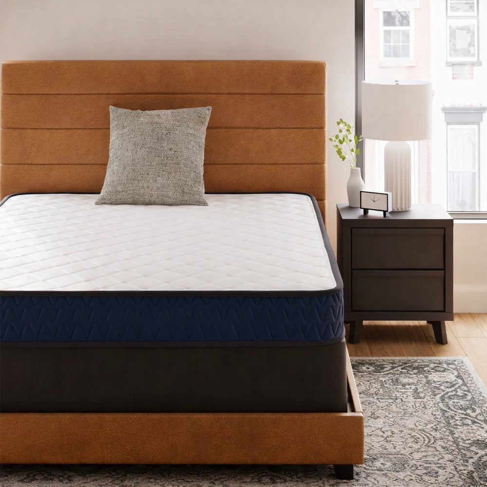 Frontal view of the Ashley 6-inch firm mattress on a tan upholstered headboard frame, ideal for a minimalist bedroom aesthetic.
