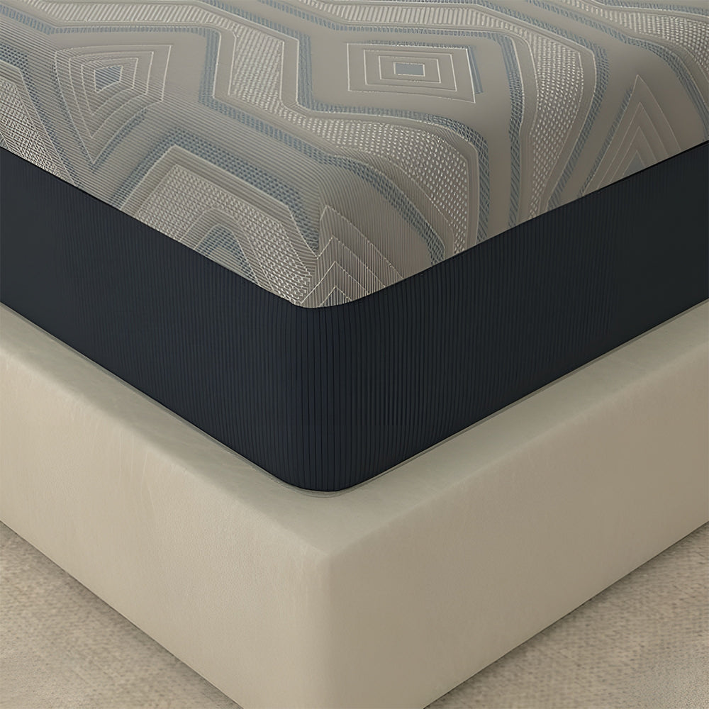 Close-up of the corner of an American Bedding Isotonic Percy Plush Hybrid Mattress featuring a grey geometric cooling cover and navy blue side panels.
