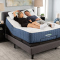 Happy couple relaxing on a GhostBed Grande 14-inch medium mattress with the head section elevated on an adjustable power base.
