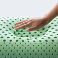 Hand pressing green peppermint memory foam showing breathable zoned ventilation for temperature control.
