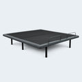 Customatic Dreamsense Synergy adjustable bed base in a flat position showing the upholstered frame and steel legs.
