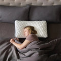 Woman side sleeping on a Malouf Quilted Convolution pillow for proper spinal alignment and cool rest.
