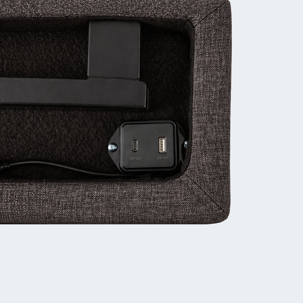 Close-up of the built-in USB and USB-C charging ports on the charcoal upholstered side rail of the Malouf M455 base.
