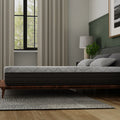 Low-profile side view of the 10-inch thick Essentials mattress by South Bay demonstrating its supportive foam layers on a minimalist wooden frame.
