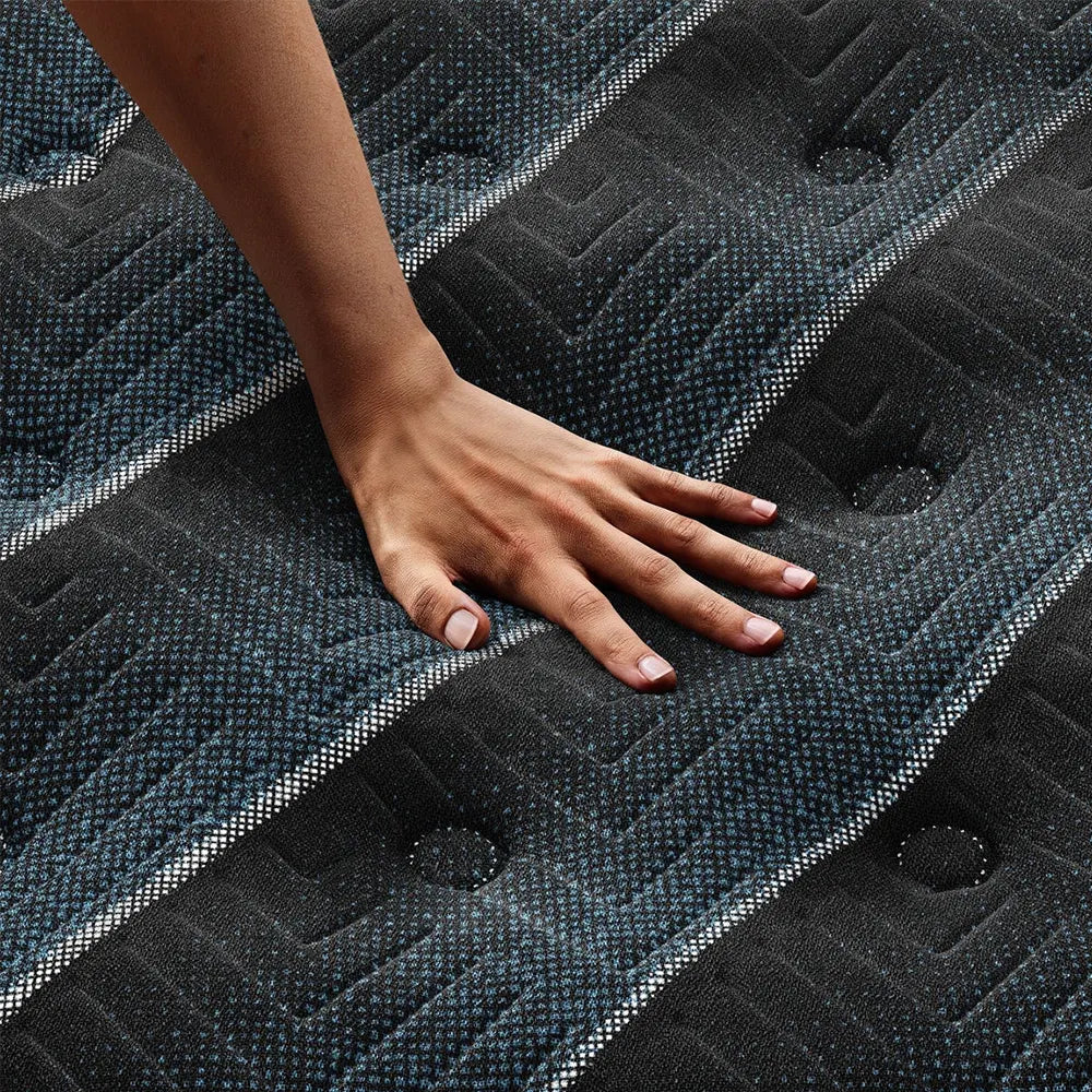 Hand on Beautyrest World Class plush mattress demonstrating contouring comfort and pressure relief.
