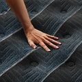 Hand on Beautyrest World Class plush mattress demonstrating contouring comfort and pressure relief.
