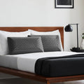 Two Malouf charcoal pillows on a modern bed, offering hypoallergenic and odor-neutralizing sleep support.
