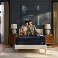 Symmetrical frontal shot of a couple relaxing on a DreamCloud Ultra 15-inch mattress in a master bedroom setting for superior motion isolation.
