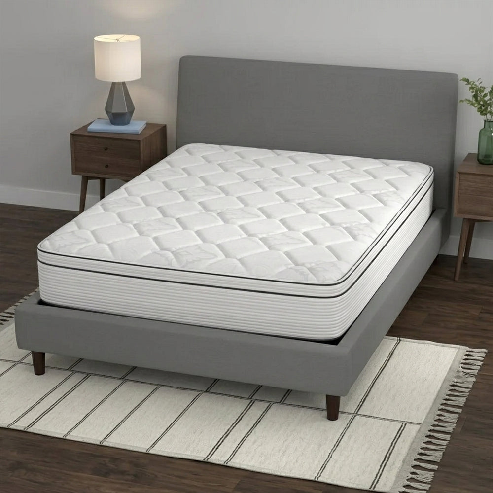 Perspective bedroom view of the American Bedding Cymbal Jingle 10" Hybrid Euro Top Mattress styled on a grey upholstered platform bed frame.
